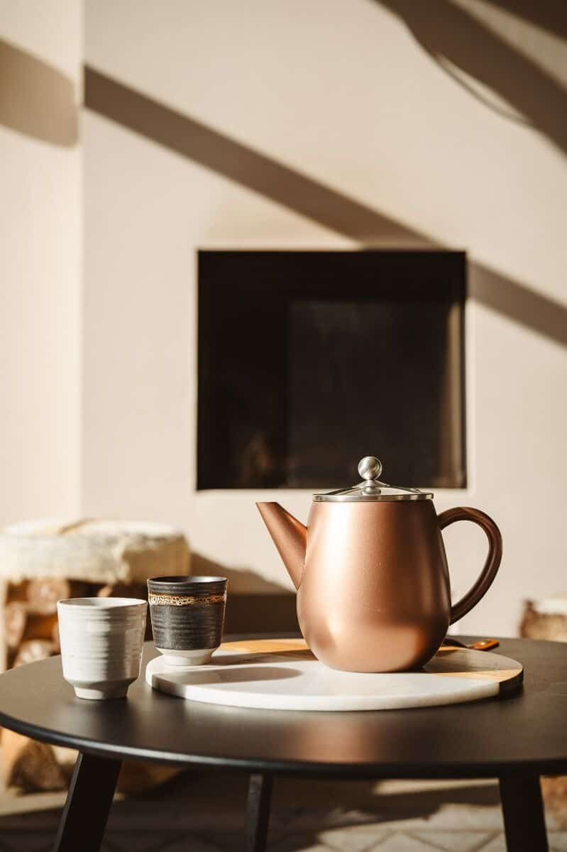 Rustieke theepot en twee bekers op een salontafel in een gezellige woonkamer sfeer.