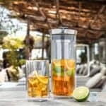 Verfrissende zomerlimonade met citrusfruit en ijs in glazen en kan op terras met houten tafel en buitendek, perfect voor ontspannen momenten bij De Heeren van 17.