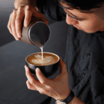 Koffie met latte art, barista schenkt melk voor een perfect melkschuim koffie, koffiebar, barista vaardigheden, kop koffie.