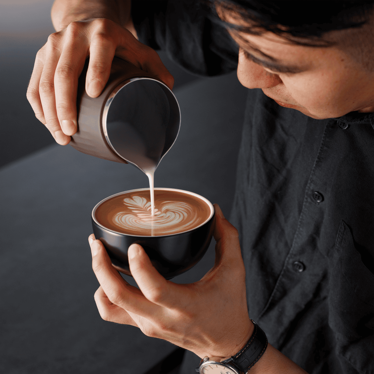 Koffie met latte art, barista schenkt melk voor een perfect melkschuim koffie, koffiebar, barista vaardigheden, kop koffie.