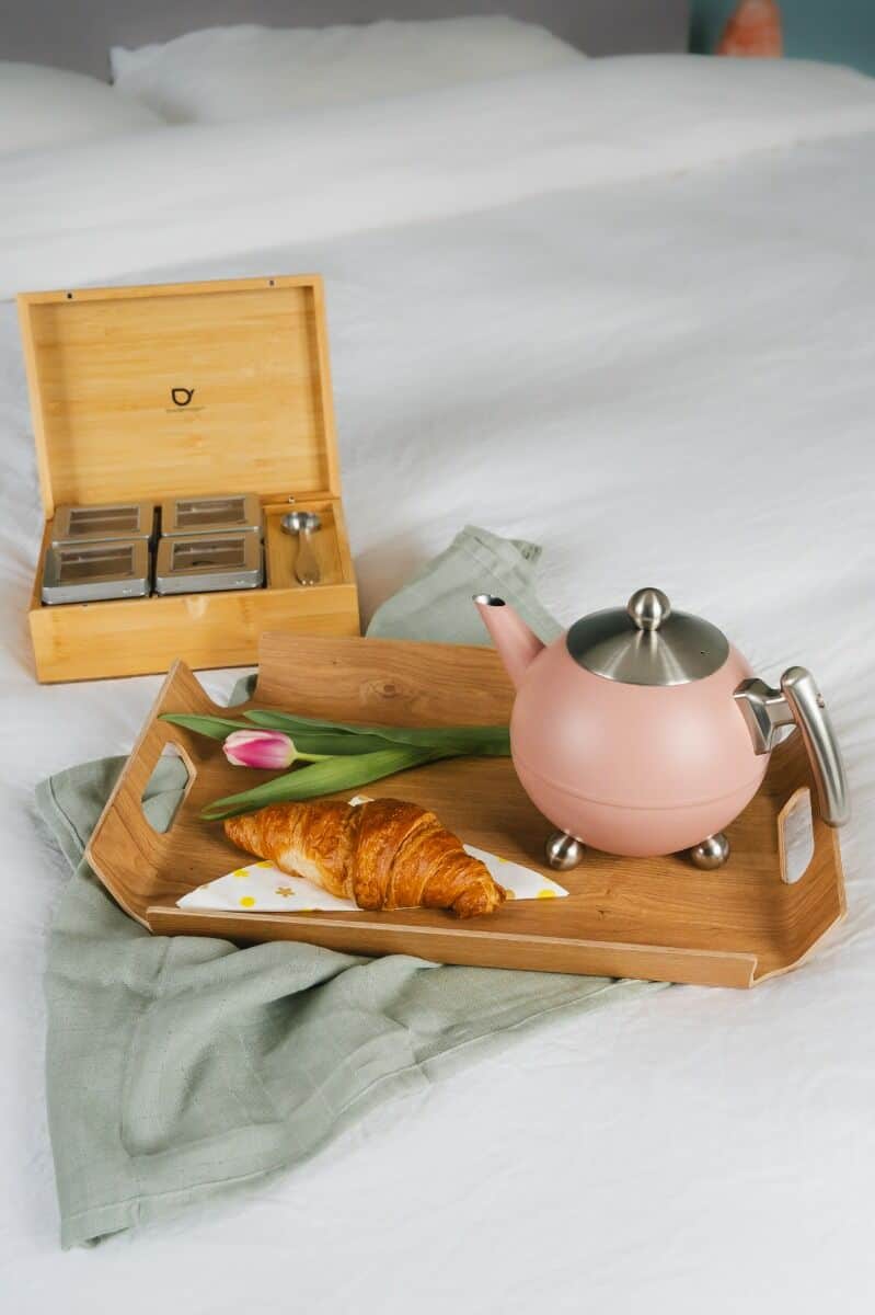 Gezellig ontbijt op bed met koffie, croissant en tulpen, perfect voor een ontspannen ochtend bij De Heeren van 17.