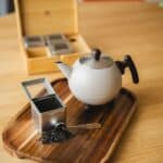 Geurthee en thee op een houten dienblad met een theepot, suiker en thee-ei, stijlvolle theeservice, perfect voor genieten van een kop thee bij De Heeren van 17.