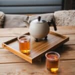 De Heeren van 17 theepot en twee glazen thee op houten dienblad op houten tafel, gezellige sfeer in buitenruimte.