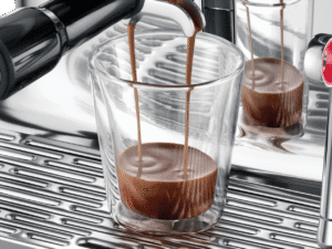 Romig hete chocolademelk wordt uit een stoomapparaat geschonken in een glas.