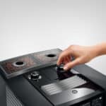 Kleine Hand die de instellingen van een moderne koffiemachine bedient, close-up van het gebruik en de bediening.
