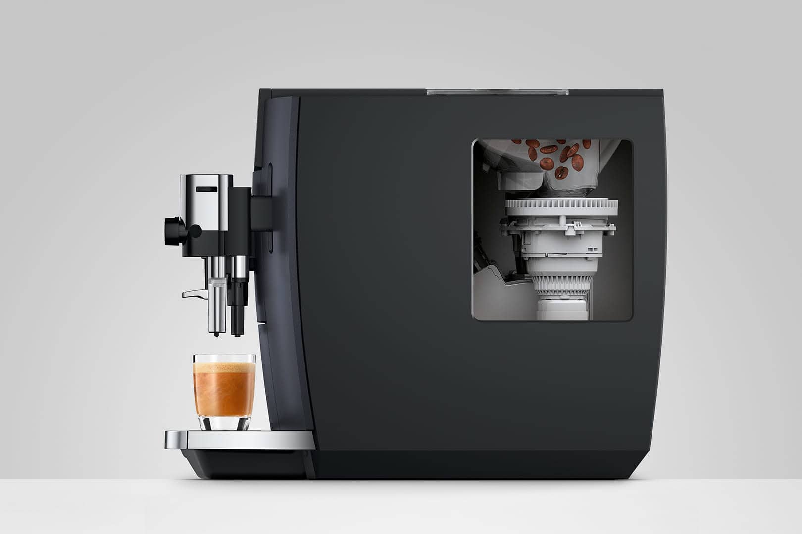 Grote zwarte koffiemachine met doorzichtige zeef en kopje verse espresso eronder, geoptimaliseerd voor koffie & horeca SEO.